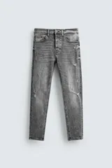 Pantalón de jean negro ajustado al cuerpo desde la cintura hasta el tobillo, de tiro medio y tejido elástico. Diseño de cinco bolsillos con lavado efecto roto y cierre frontal con cremallera y botón.