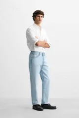 Pantalón de jean celeste de corte slim fit y tapered, con cinco bolsillos, efecto lavado y cierre frontal con cremallera y botón.