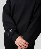 Buzo color beige con cuello alto, confeccionado en 60% algodón y 40% poliéster. Presenta bordado en la manga y no tiene felpa.