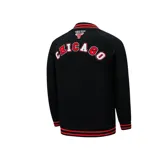 Campera negra con detalles en rojo y blanco, con cierre frontal y bolsillos laterales. Presenta el logo de los Chicago Bulls en el pecho y letras en el brazo izquierdo.