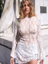 Vestido corto blanco de encaje elastizado, con mangas largas acampanadas y escote redondo. Incluye forro interior.