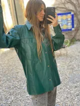 Campera de cuero color verde con cuello camisero, cierre frontal con botones a presión, dos bolsillos de parche en el pecho y corte recto. Estilo gipsy.