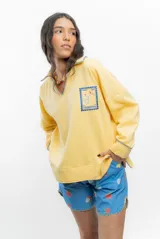 Buzo amarillo de algodón con cuello polo, mangas largas y bordado de un sello con motivos marinos.