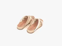 Sandalias bajas de cuero color beige con tiras cruzadas en cuero color blanco.