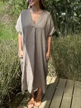 Vestido largo color beige de lino italiano, con escote en V, mangas cortas y bolsillos laterales.