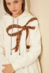 Buzo negro de frisa oversize con capucha y bordado de moño print animal en gamuza en el delantero.