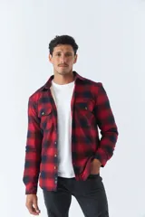 Sobrecamisa de algodón para hombre con interior de corderito, estampado a cuadros en tonos negro, blanco y azul. Tiene cierre de botones, bolsillos tipo cartera y logo en goma. El modelo usa talle M.