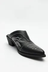 Zuecos negros de cuero sintético con punta fina, bordados en la capellada y taco cuadrado de 5cm de alto.