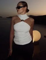 Top blanco sin mangas con cuello halter y detalle de anillo metálico en el centro.