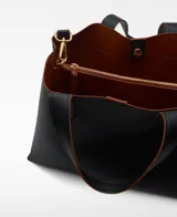 Bolso tipo tote grande color marrón, con doble asa de mano y correa larga extraíble. Interior con dos compartimentos y bolsillo central con cierre.