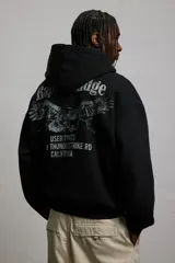 Canguro negro con capucha, corte holgado y bolsillo tipo canguro. Confeccionado en tejido de mezcla de algodón con interior cepillado suave. Remate acanalado en puños y bajo.