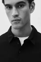 Chomba negra de piqué de algodón, corte slim fit, con cuello clásico, tapeta de dos botones y mangas cortas.
