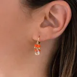 Aros dorados tipo argolla con dijes colgantes de cuentas rojas y cristal facetado.