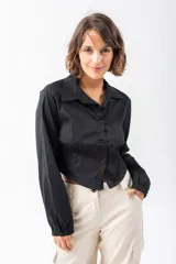 Camisa corta negra de algodón y elastano, con cuello clásico, mangas largas con puños elásticos, cierre frontal con botones y cintura elastizada.