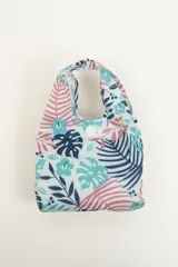 Tote bag de tela con estampado de hojas de palmera en tonos azul, celeste y rosa. Tiene doble asa superior y cierre con botón a presión.