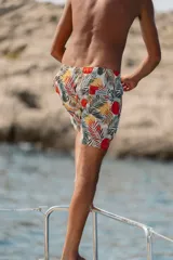 Short de baño con estampado de hojas de palmera y círculos rojos.