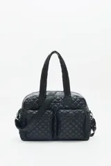 Bolso marrón con diseño matelassé, doble asa corta, correa larga desmontable y dos bolsillos frontales. Incluye llavero de corazón y dijes desmontables.