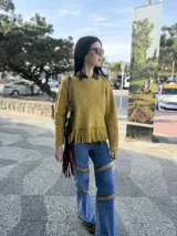 Sweater tejido en lana color borgoña, con cuello redondo y terminación con flecos.