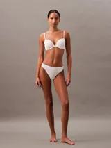 Conjunto de ropa interior Calvin Klein color blanco, compuesto por un corpiño con aro y breteles regulables, y una bombacha colaless de microfibra con cintura elástica.