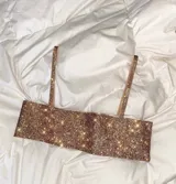 Top corto dorado con lentejuelas, breteles finos y espalda descubierta con cierre de cadena.