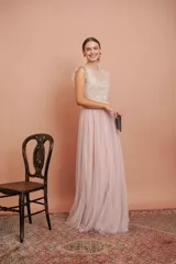 Vestido largo de fiesta color rosado con lunares blancos. Tiene cuerpo de micro tul bordado con volados en los hombros y falda de tul con forro. Incluye cinturón de raso al tono.