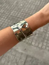 Brazalete ancho plateado de alpaca con textura martillada y diseño abierto.