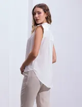 Blusa negra de gasa marca Tahari, con cuello a la base con solapa, abertura central con botones ocultos y detalle plisado en hombros.