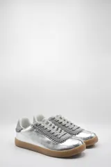 Zapatilla plateada de cuero con detalles de gamuza gris y costuras visibles.