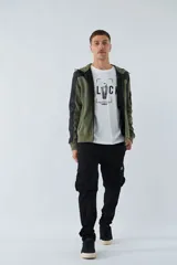 Campera verde militar para hombre con capucha ajustable, cierre frontal completo, bolsillos laterales con cierre y logo estampado en el pecho. Presenta detalles en negro en la parte superior del pecho, hombros y mangas.