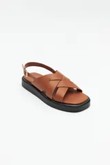 Sandalias negras de símil cuero con agarre ajustable en el talón y capellada entrelazada. Plataforma de 3 cm de alto.