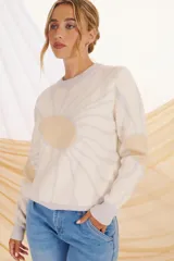 Buzo de punto en tonos lila y violeta, con diseño gráfico de un sol en el frente.