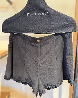 Short negro de lino con cintura alta y detalle de encaje festoneado en el ruedo.