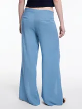 Pantalón ancho color blanco, de lino y viscosa, con tajos y lazos en la botamanga.