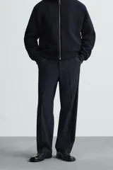 Pantalón de vestir negro, corte recto (straight fit), con cierre frontal de botón y cremallera. Presenta bolsillos delanteros, bolsillos traseros de vivo y un bolsillo de vivo adicional en la pernera.