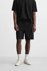 Bermuda negra de corte relaxed fit, con cintura elástica ajustable con cordón, bolsillos frontales y bolsillo trasero de parche.