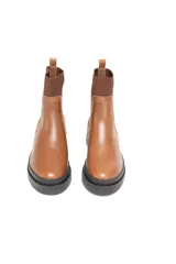 Bota Chelsea color marrón, de cuero liso, con elásticos laterales al tono y suela chunky de goma negra antideslizante.
