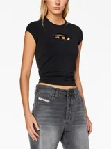 Camiseta negra de manga corta, corte ajustado y cuello redondo. Presenta un recorte ovalado en el centro del pecho con un detalle metálico con el logo de Diesel.