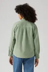 Camisa Levi's de pana color verde claro, corte oversize, con cuello clásico, cierre frontal con botones marrones, dos bolsillos de parche con solapa abotonada en el pecho y mangas largas con puños abotonados.