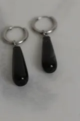 Par de aros colgantes con argolla de acero quirúrgico hipoalergénico y dije en forma de gota de piedra natural color marrón.