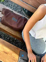Bolso tote marrón de gabardina con detalles de cuero negro, asas cortas y cierre superior.