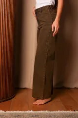 Jean wide leg color marrón oscuro con efecto oxidado, tiro alto y cierre de botón y cremallera.