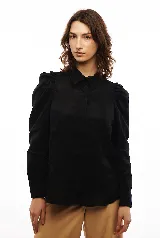 Camisa blanca de lino con corte clásico, cuello camisero, mangas largas con puños abotonados y volados en los hombros.