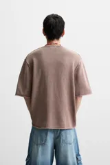 Camiseta relaxed fit de punto color marrón con efecto lavado, cuello redondo con cierre frontal de botonadura y manga corta.