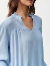 Blusa blanca de manga larga con escote en V y textura arrugada.