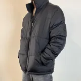 Campera puffer color beige con cierre frontal y cuello alto. Diseño acolchado con bolsillos laterales.