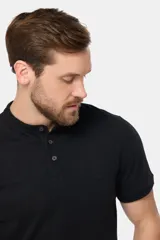 Remera de manga corta color azul grisáceo con cuello mao y tapeta de botones. Los puños de las mangas y el cuello son de color azul marino contrastante. Presenta un pequeño logo bordado en el pecho.