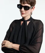 Blusa negra de chiffon con cuello alto con lazo, mangas largas con puños ajustados, detalle de volado delantero y volado en encaje.