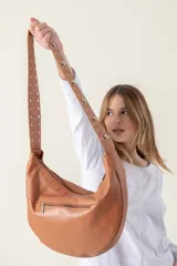 Cartera negra tipo banana confeccionada en cuero vacuno, con cierre superior y asa con tachas plateadas.