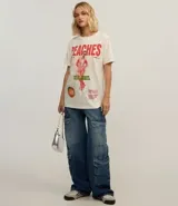 Remera color crudo de algodón con estampado frontal de Justin Bieber y la palabra "Peaches" en rojo.