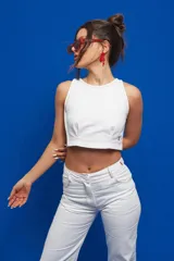 Pantalón de gabardina color blanco, de corte recto y tiro medio/alto, con bolsillos delanteros y traseros al estilo jean. Los pespuntes en contraste son de color rojo.